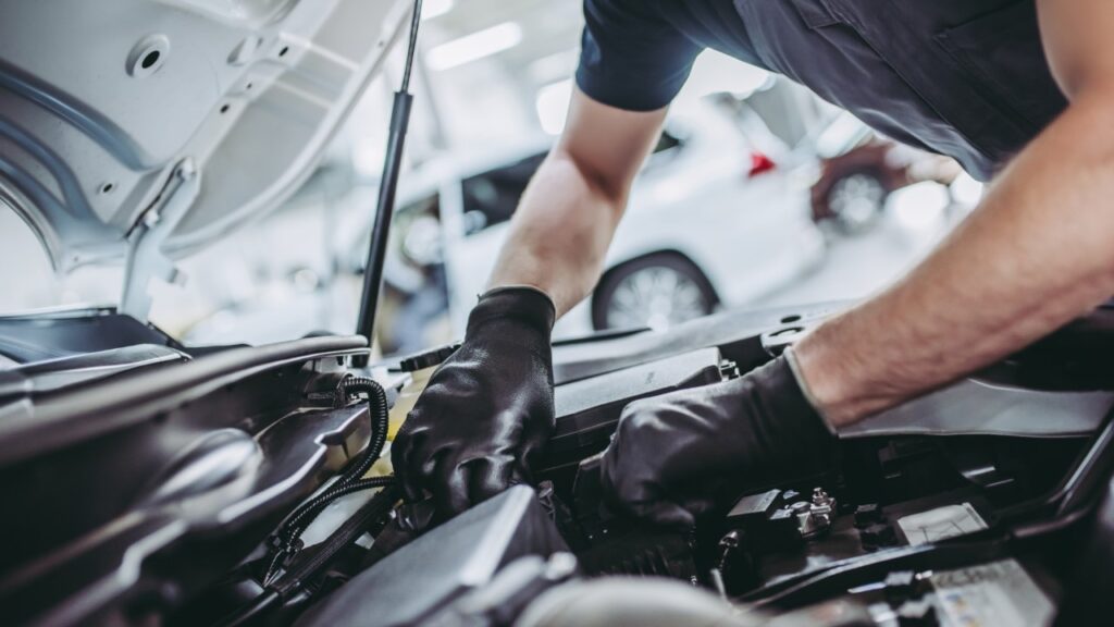 hands working on the engine of a trailer truck